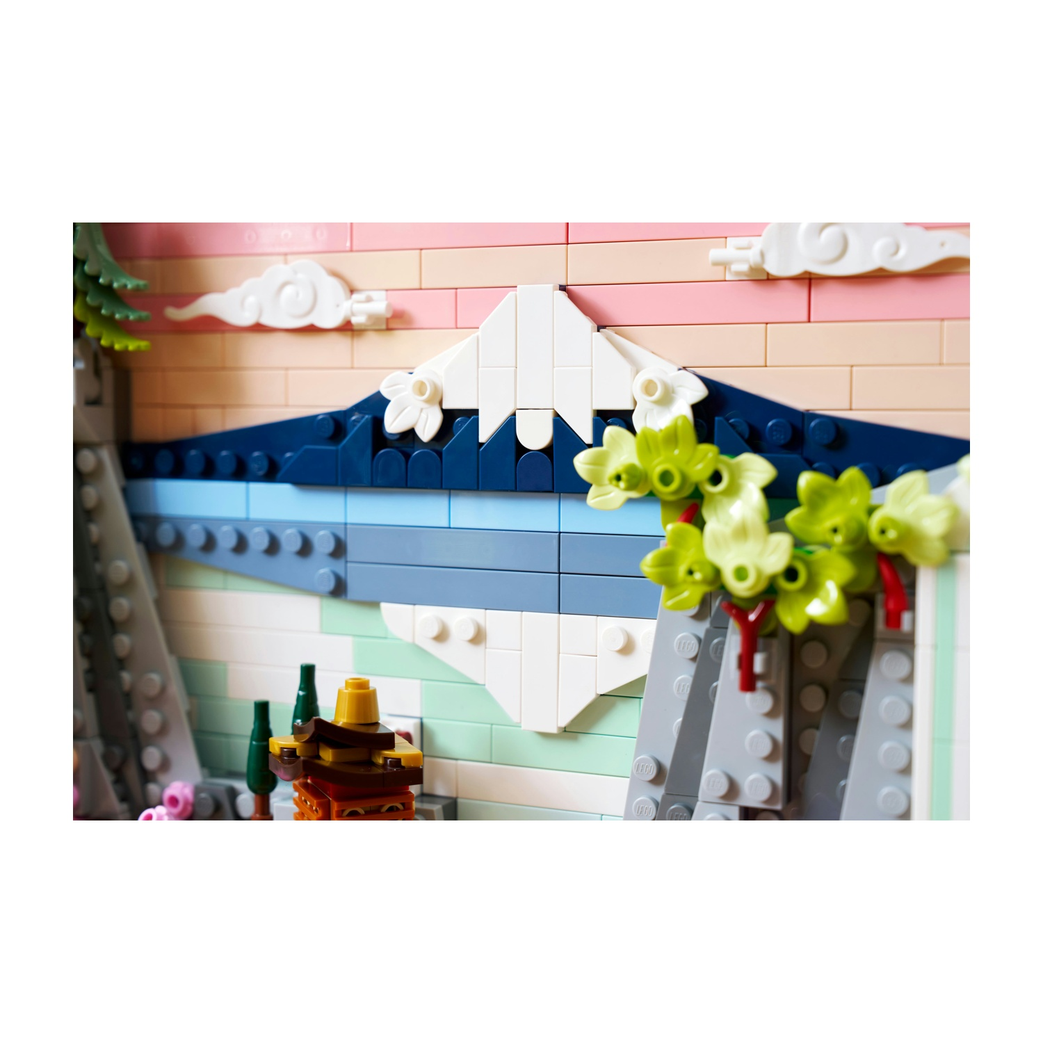 Scena Lego di un paesaggio montano con acqua blu e nuvole bianche. Il primo piano presenta foglie verdi e steli rossi.
