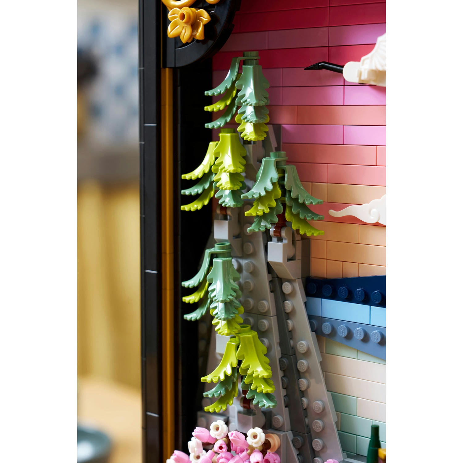 Scena Lego con alberi verdi e fiori rosa. Lo sfondo ha un gradiente di rosa e arancione. Una gru nera vola sulla scena.