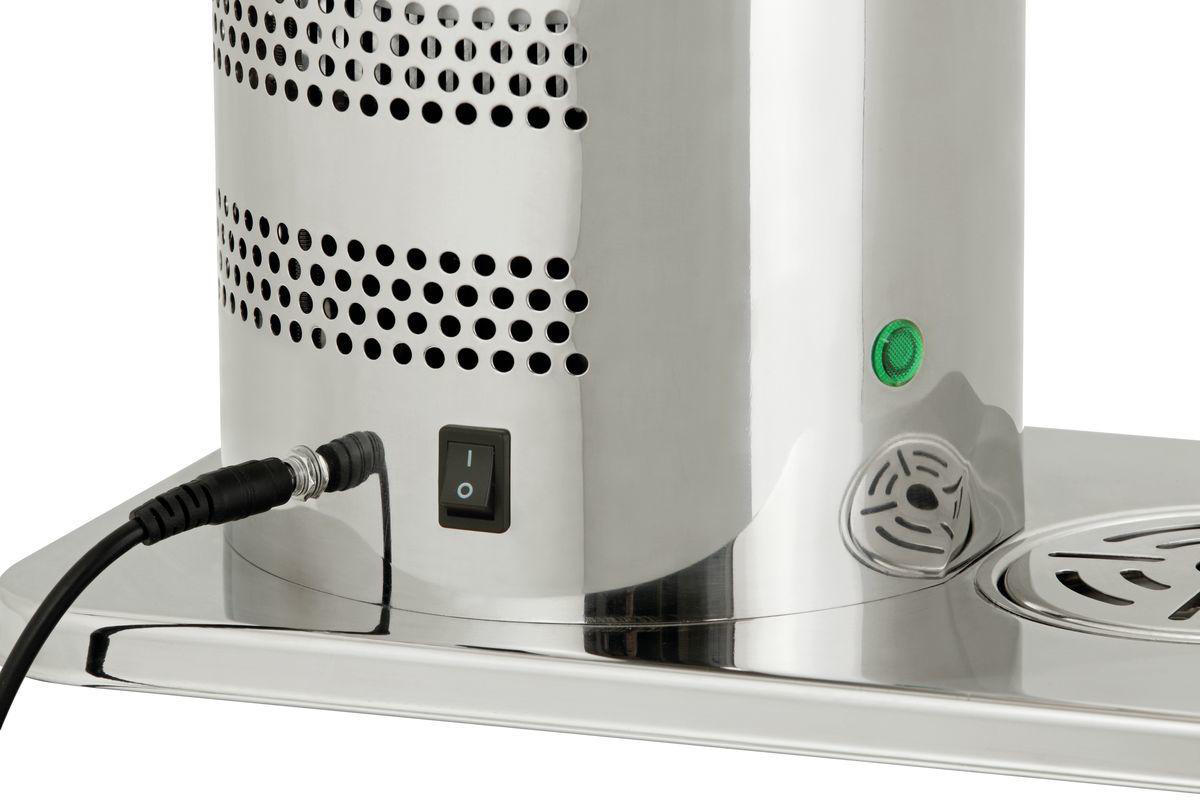 Nahaufnahme eines silbernen Geräts mit Netzschalter, grüner Taste und schwarzem Kabel. Perforierte Metalldetails und eine Ablage sind sichtbar.