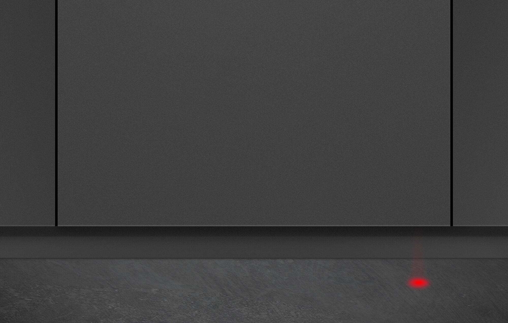 Graue Wand mit schwarzer Linie, strukturierte graue Oberfläche und rotes Licht unten.