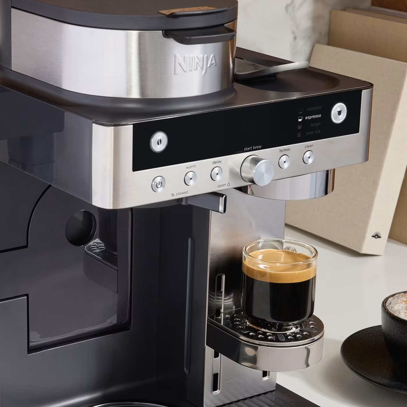 Una macchina per espresso Ninja con un bicchiere di espresso. I pulsanti includono espresso, avvia infusione e pulizia.
