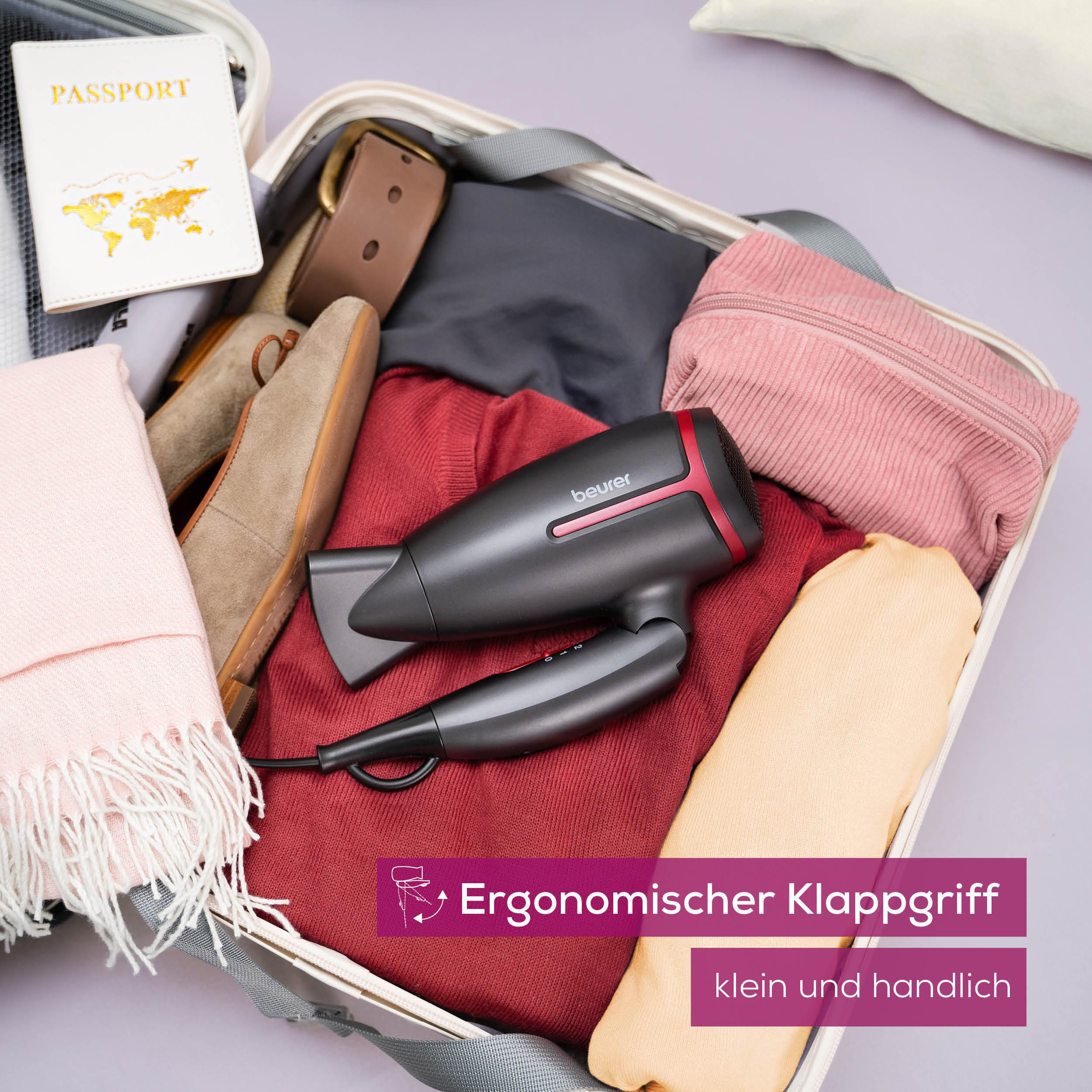 Koffer mit Kleidung, Schuhen, Reisepass und einem schwarzen Haartrockner mit roten Details, reisefertig.