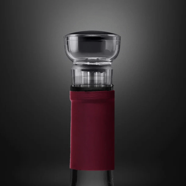 Una botella de vino con un conservador de vino transparente y con tapa negra. La botella tiene una etiqueta roja en el cuello.