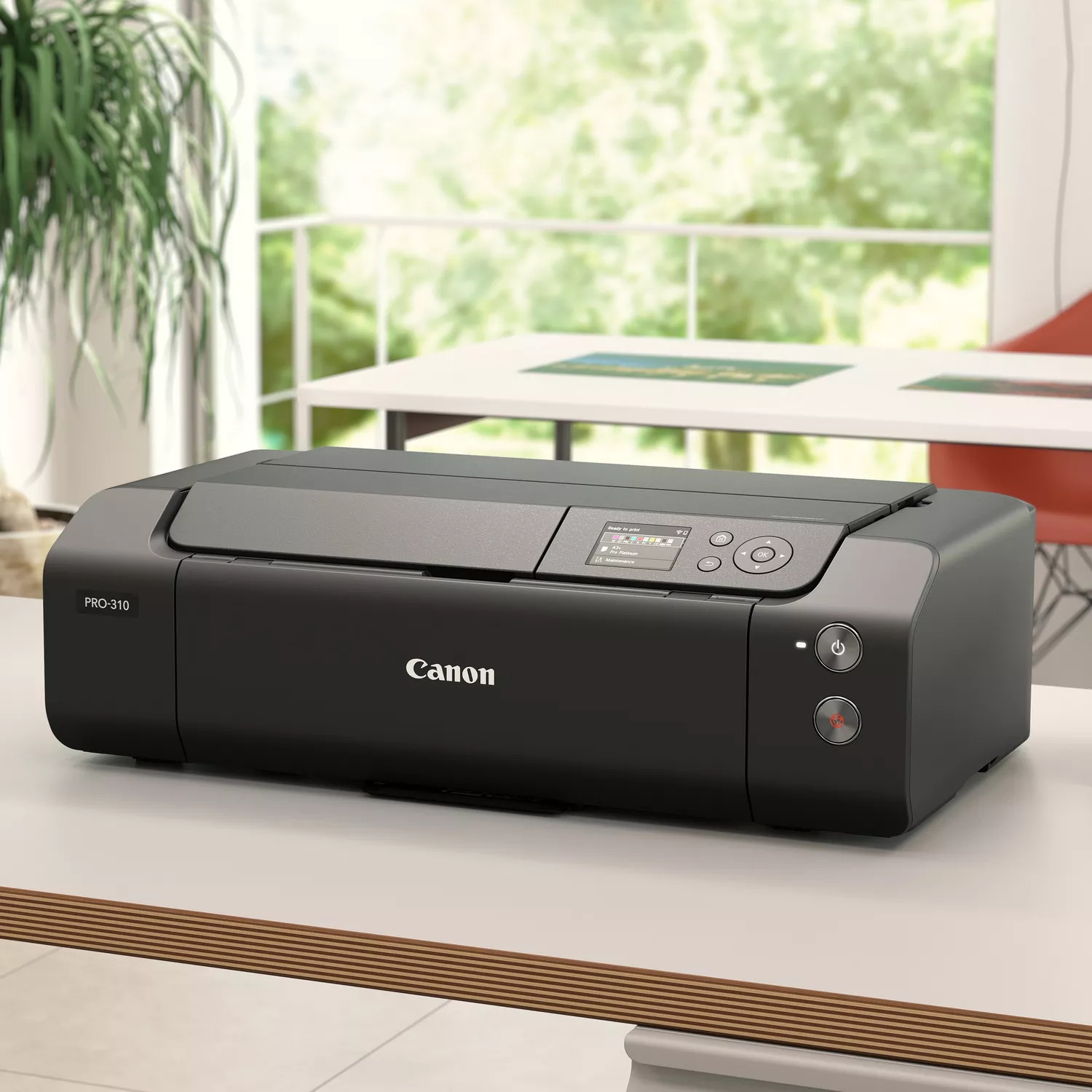 Una impresora Canon Pro-310 negra sobre una mesa blanca. En el fondo, una ventana con follaje verde.