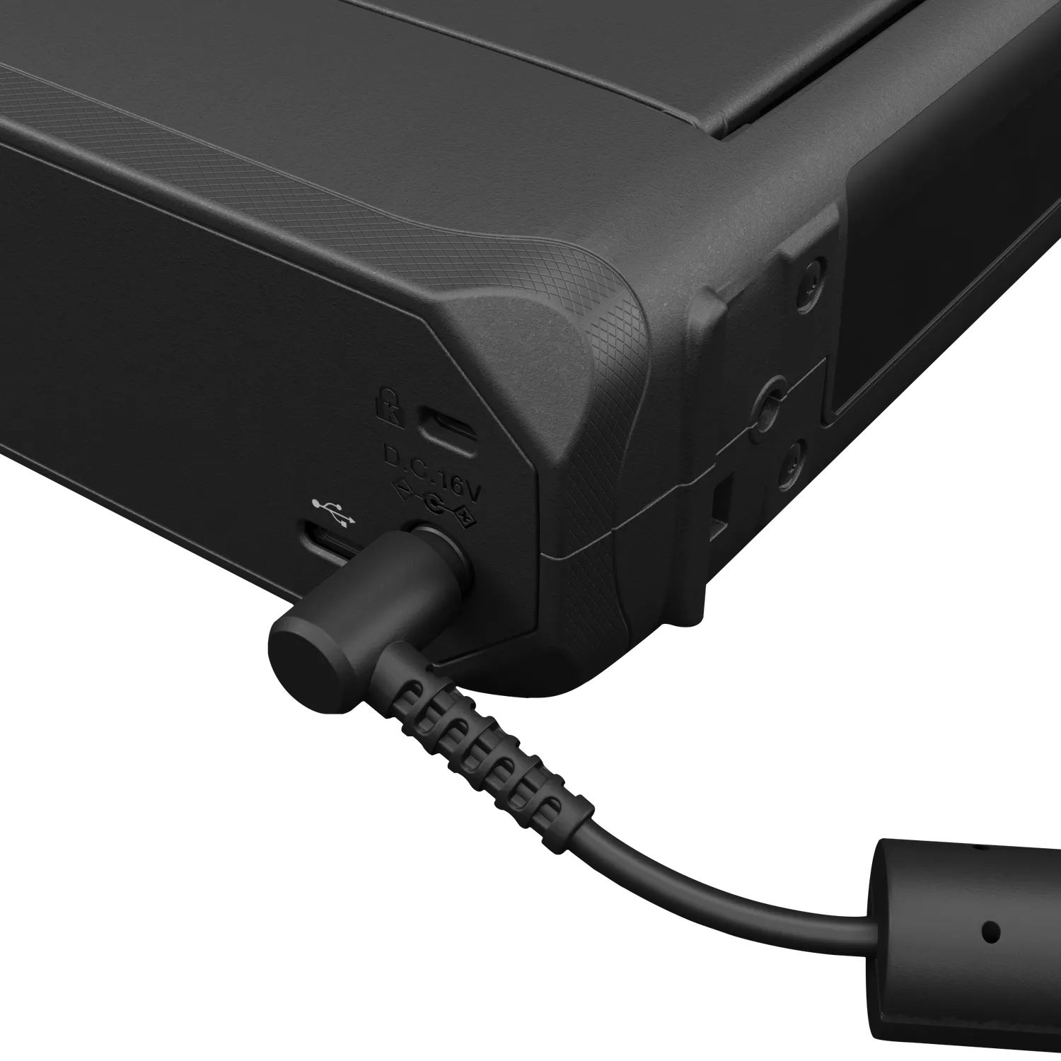 Primer plano de un dispositivo negro con un adaptador de corriente enchufado. Detalles incluyen puertos, entrada de energía y el cable.