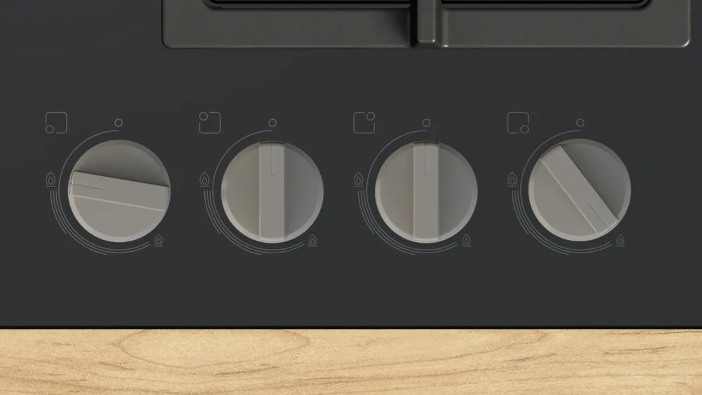 Zbliżenie czarnej płyty grzejnej z czterema srebrnymi pokrętłami. Każde pokrętło ma biały wskaźnik. Drewniana powierzchnia na dole.