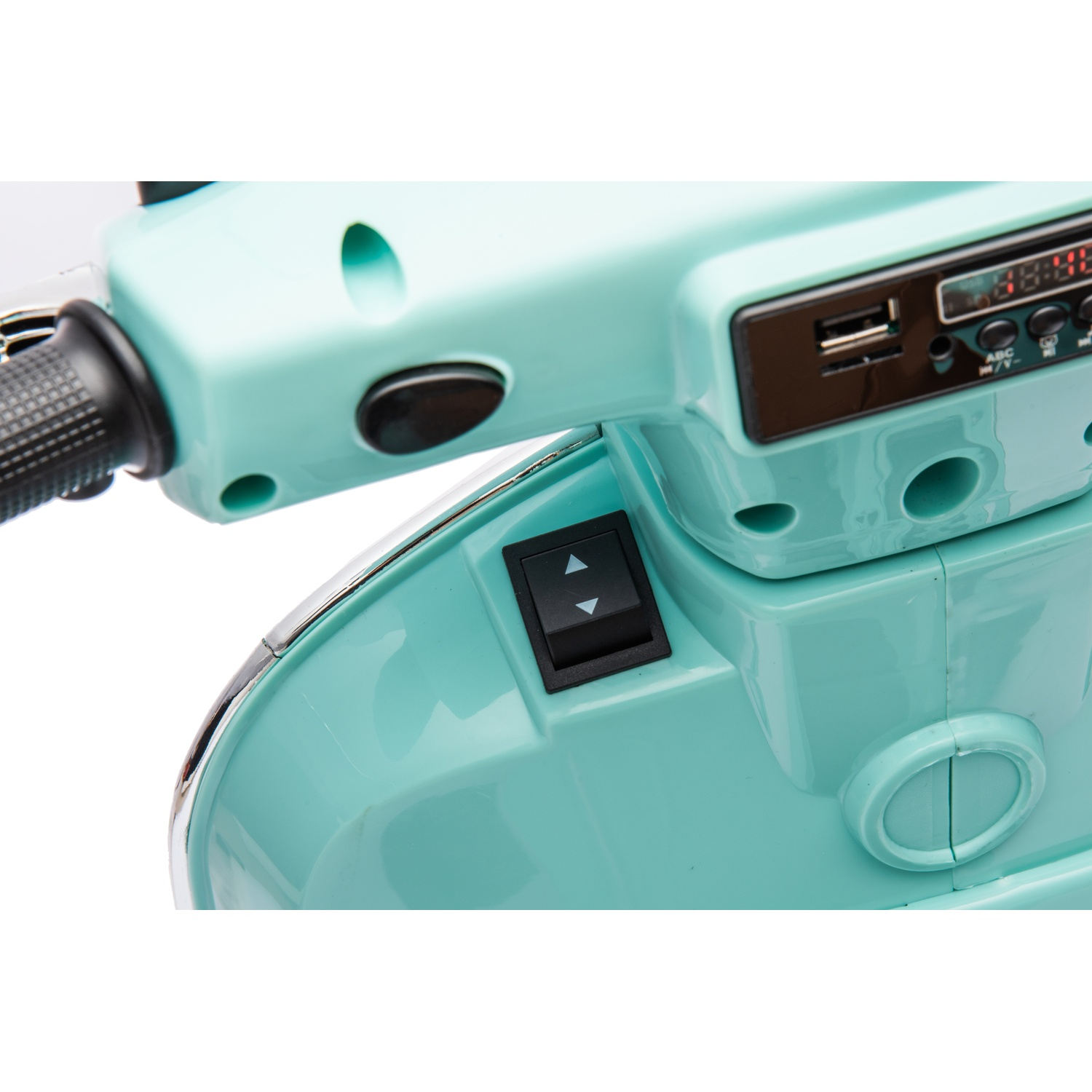 Gros plan sur le tableau de bord d'un scooter turquoise. Il comporte un interrupteur noir, un port USB et un affichage numérique, sur fond blanc.