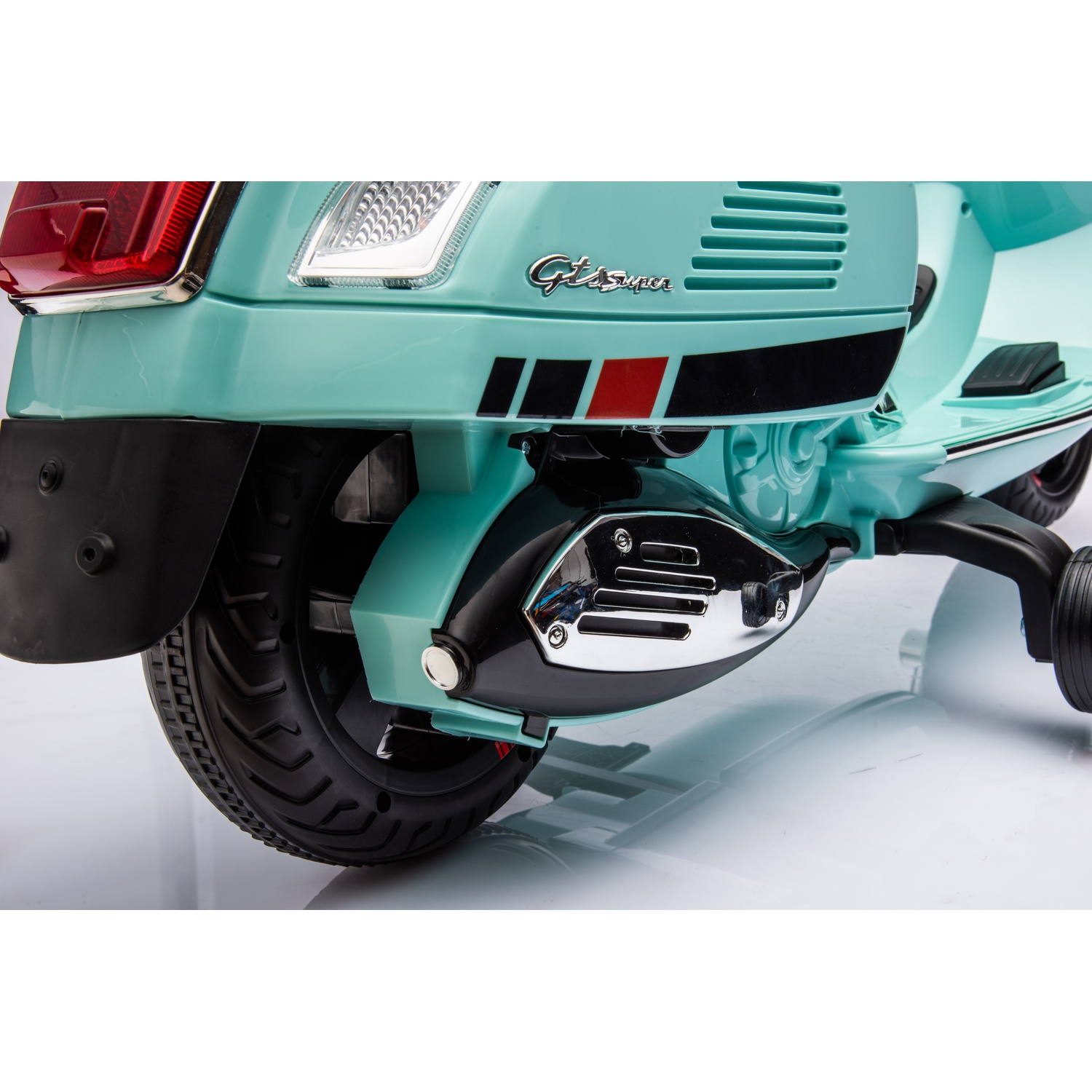 Gros plan d'un scooter turquoise. Les détails incluent des pneus noirs, des pièces de moteur chromées et un feu arrière rouge. Le scooter a des roulettes.