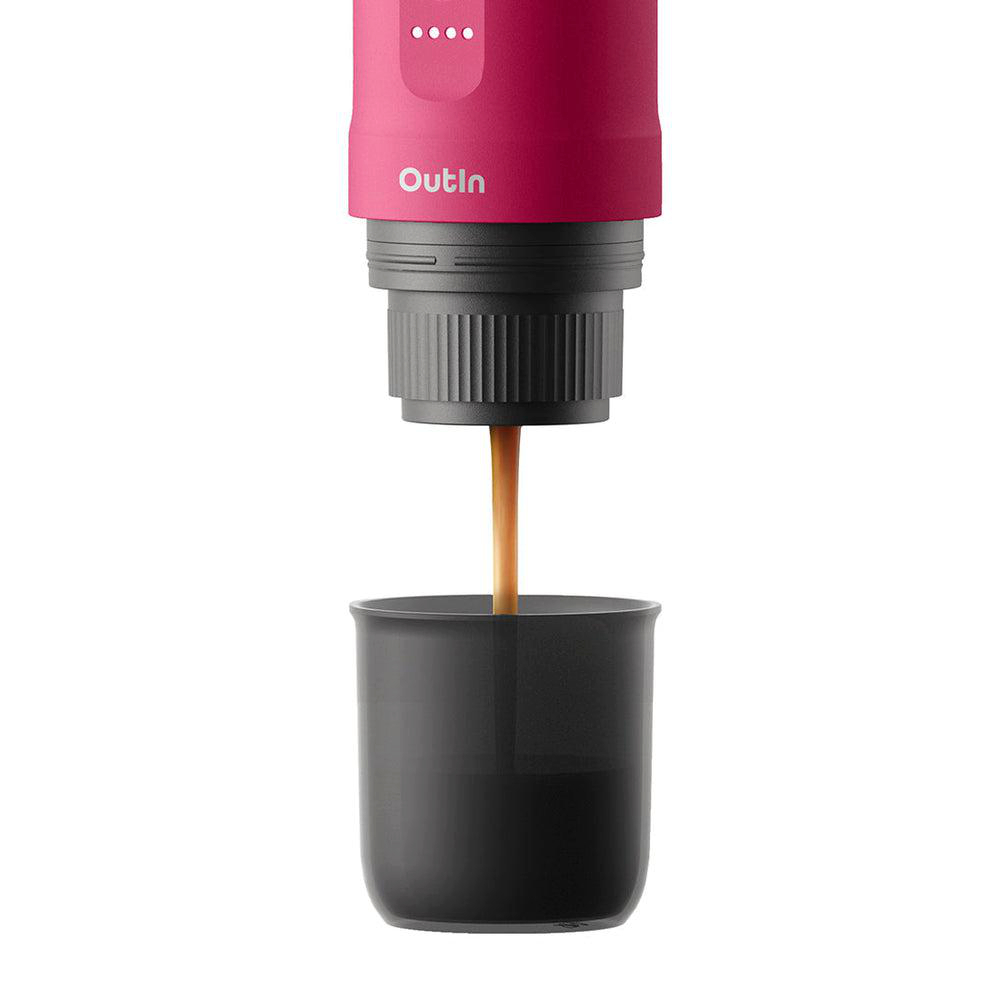 Eine Kaffeemaschine, die Kaffee in eine schwarze Tasse ausgibt. Die Maschine ist rosa und grau. Das Outin-Logo ist sichtbar.