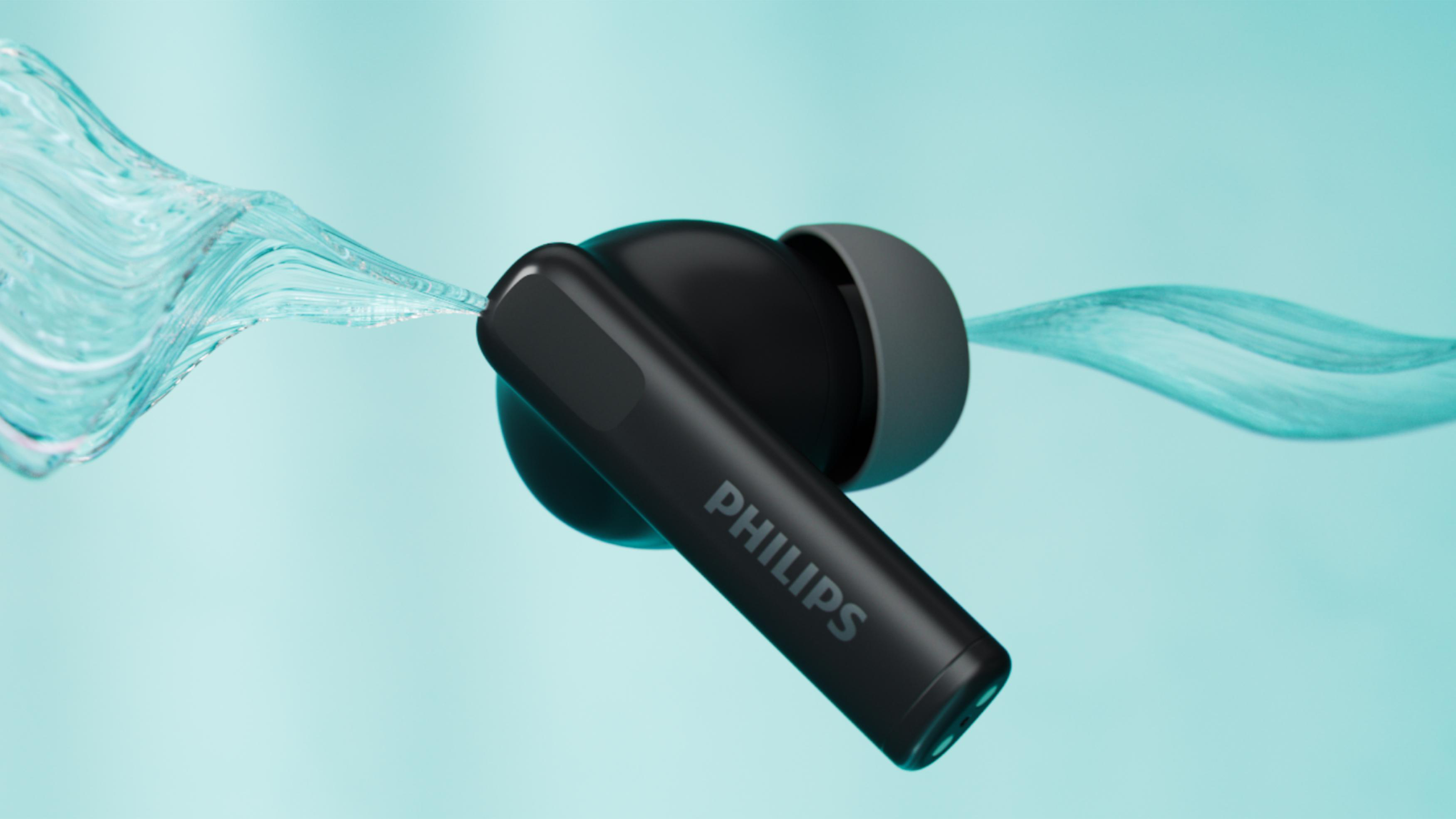 Schwarze Philips-Ohrhörer in fließendem Wasser. Die Ohrhörer sind im Fokus, Wasser in Bewegung, auf hellblauem Hintergrund.