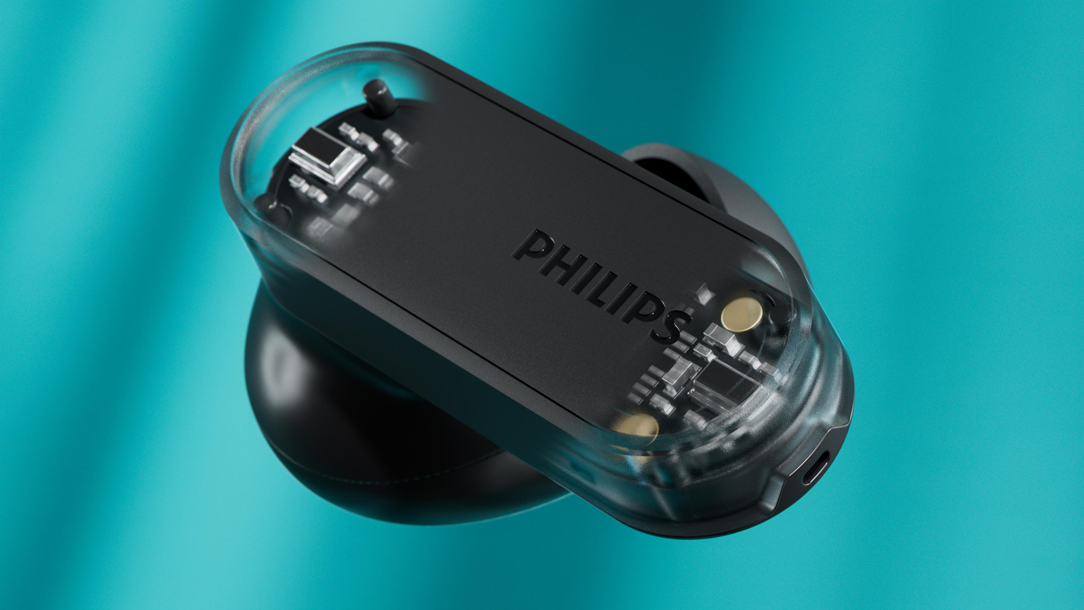 Ein schwarzer Philips-Ohrhörer mit transparentem Oberteil schwebt vor einem türkisfarbenen Hintergrund. Das Philips-Logo ist sichtbar. Komponenten werden gezeigt.