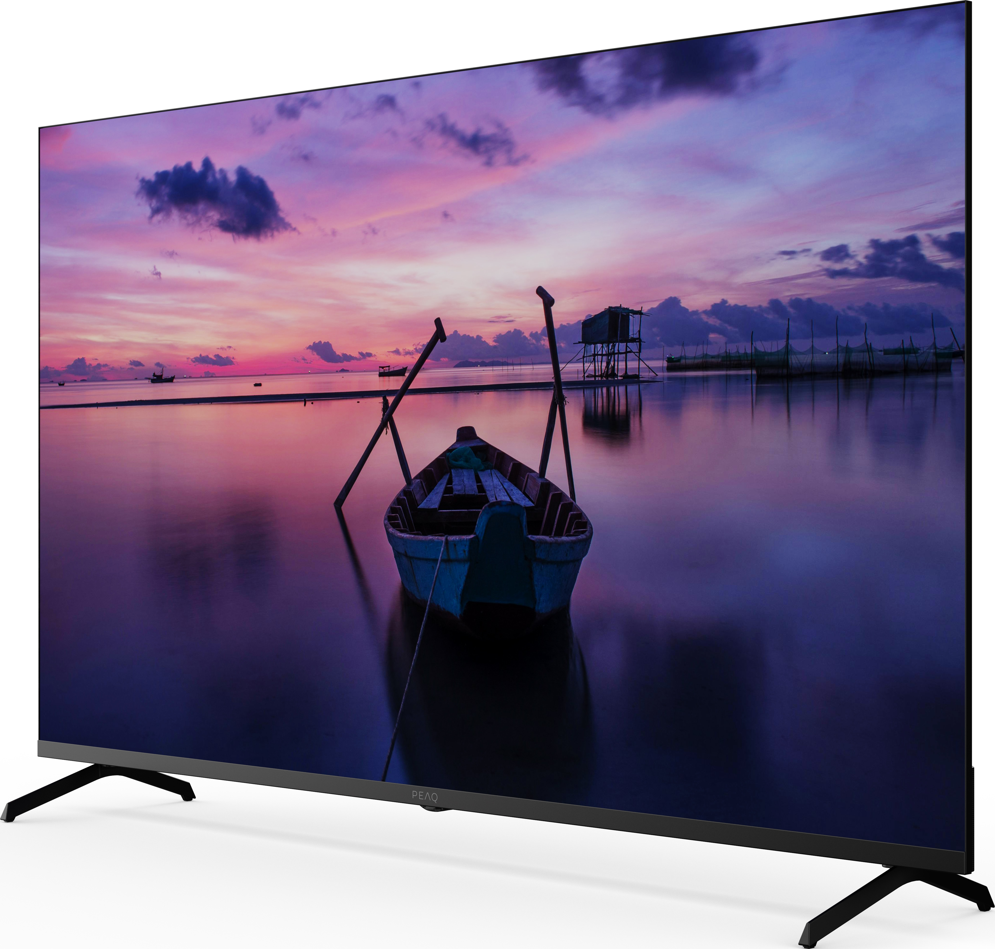 L'écran de télévision affiche un coucher de soleil sur l'eau avec un bateau. L'eau reflète les couleurs du ciel et les nuages.