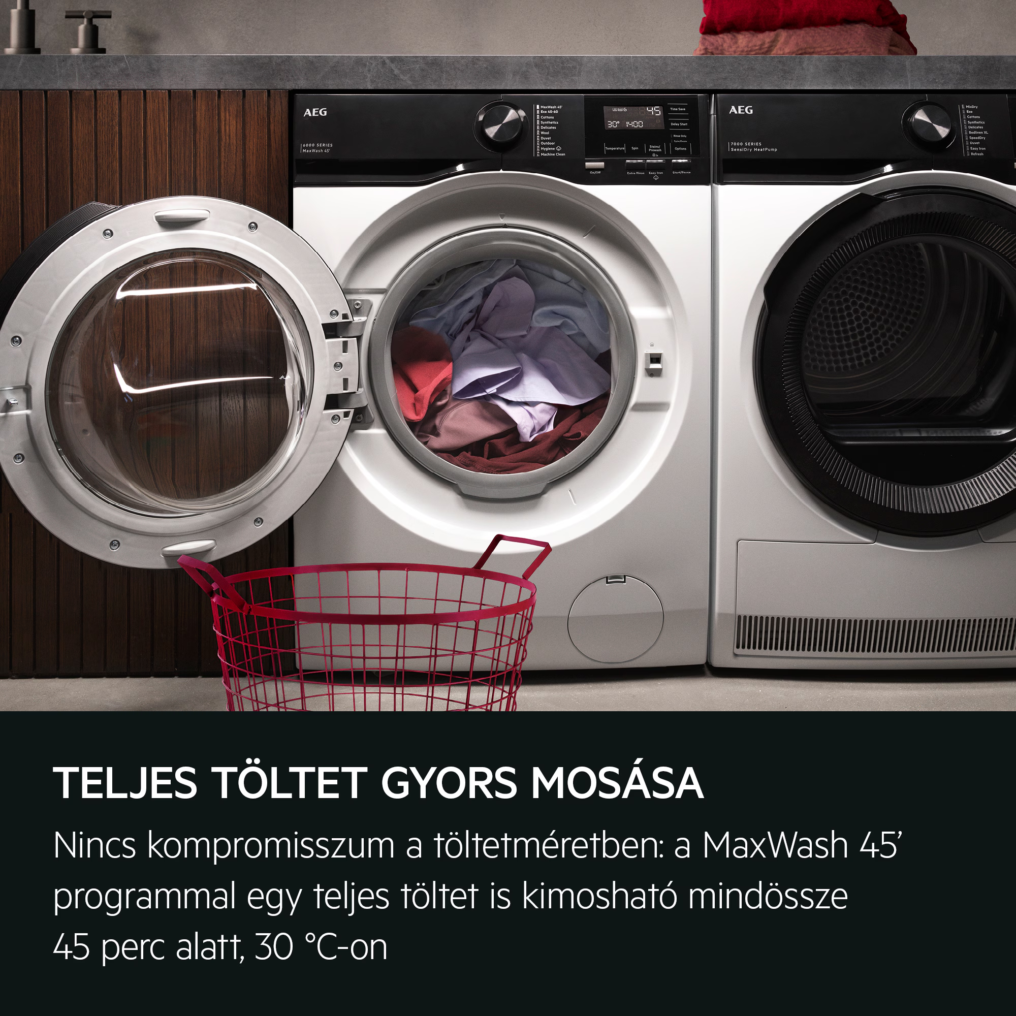 Mosógép nyitott ajtóval és ruhákkal. Elöl egy rózsaszín kosár. Fekete-fehér gépek.