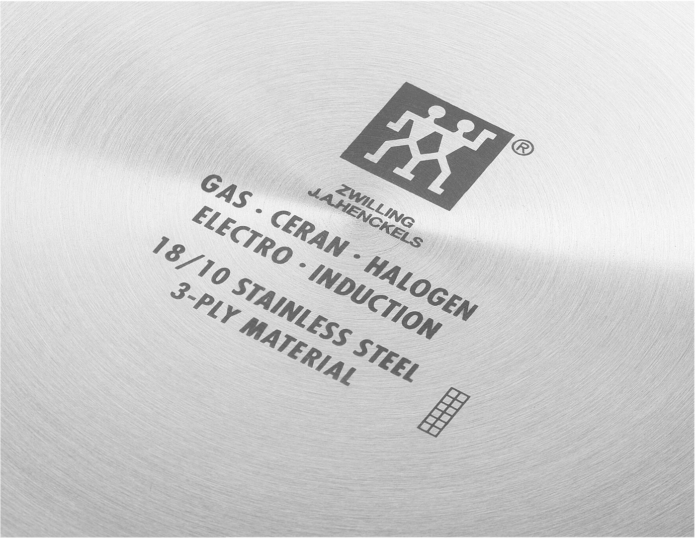 Nahaufnahme eines Edelstahlpfannenbodens. Er enthält gedruckten Text über Materialien und Kompatibilität, mit dem Zwilling J.A. Henckels Logo.