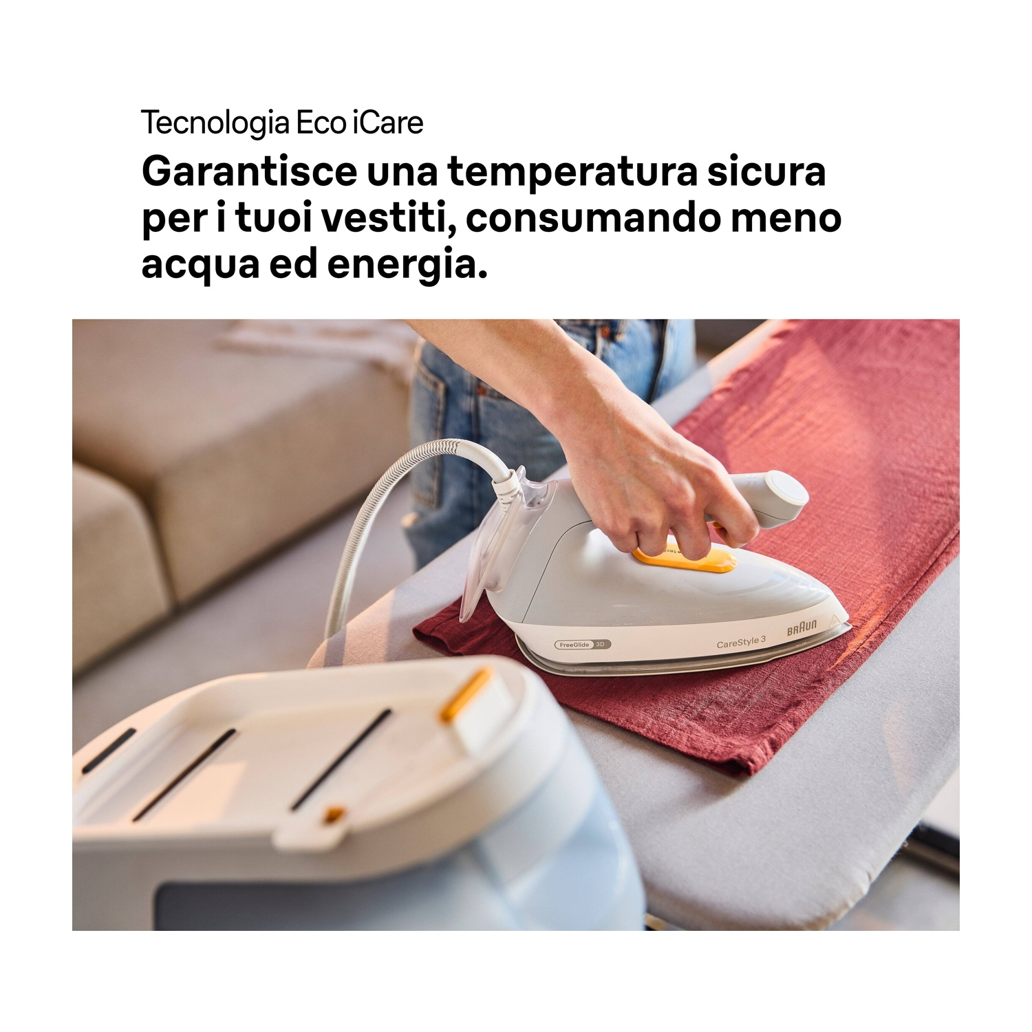 Una persona stira un tessuto rosso con un ferro da stiro grigio Braun. Il ferro è su un'asse da stiro. È visibile una stazione vapore bianca e grigia.