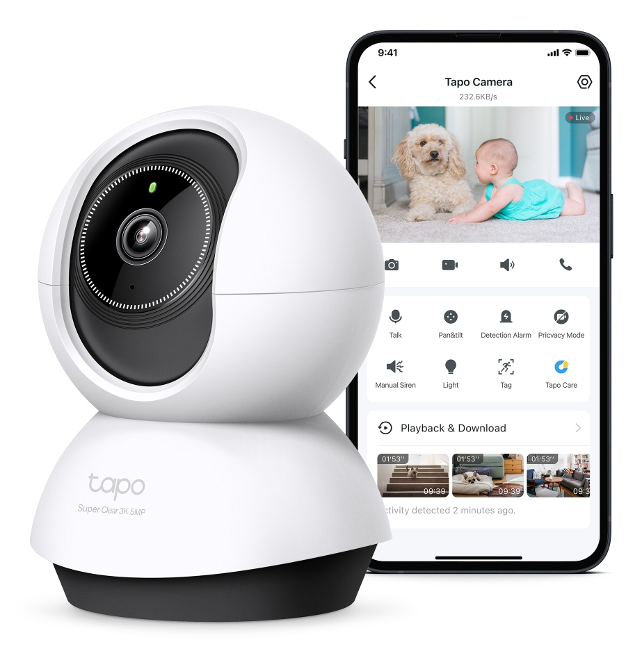 Una cámara Tapo blanca con lente negra está junto a un teléfono que muestra un bebé y un perro en la pantalla.