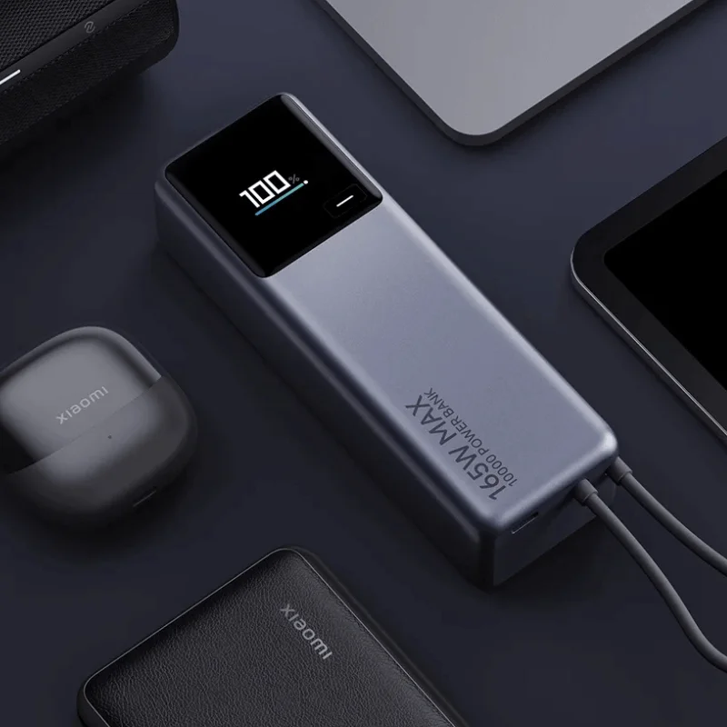 Un power bank muestra 100%. Otros elementos incluyen auriculares inalámbricos, una tableta y un power bank texturizado, todo sobre una superficie oscura.
