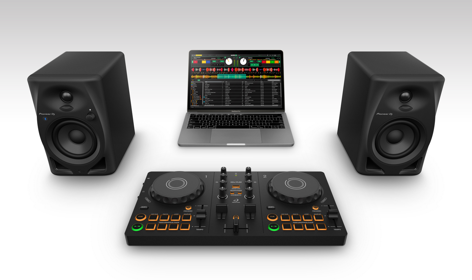 Configuración de DJ con portátil mostrando software de música, dos altavoces y un controlador de DJ sobre una superficie blanca.