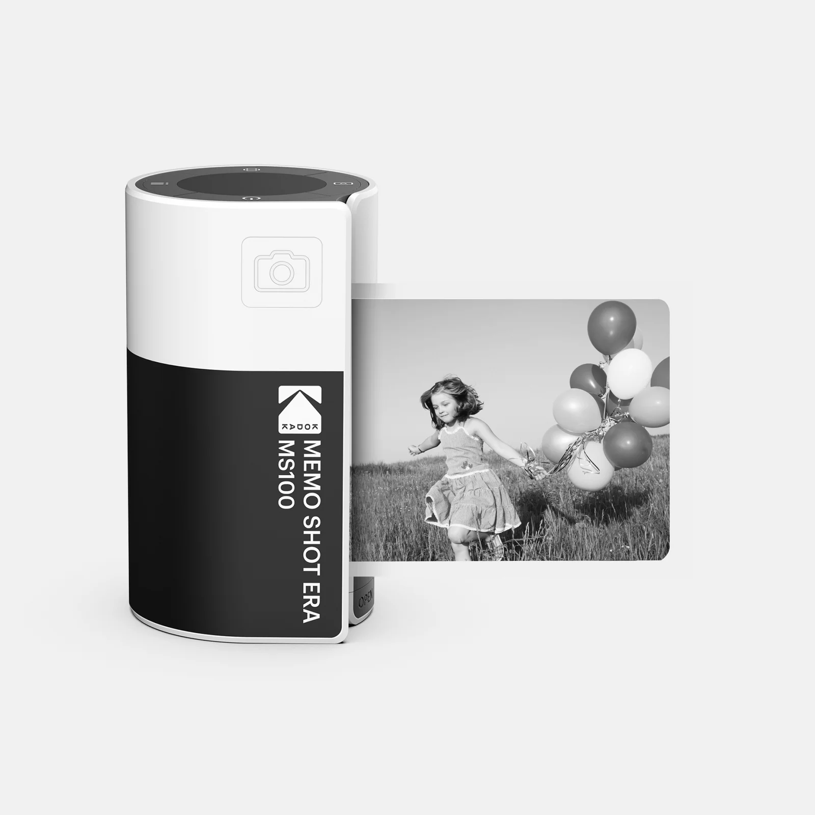 Bir Kodak Memo Shot Era fotoğraf makinesi, tarlada balonlarla koşan bir kızın fotoğrafının yanında.