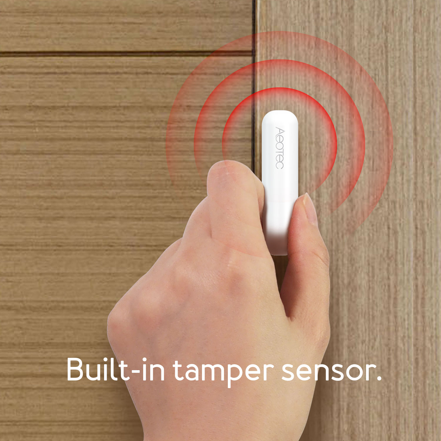 Eine Hand hält einen weißen Aeotec-Sensor in der Nähe einer Holztür. Rote Kreise gehen vom Sensor aus.