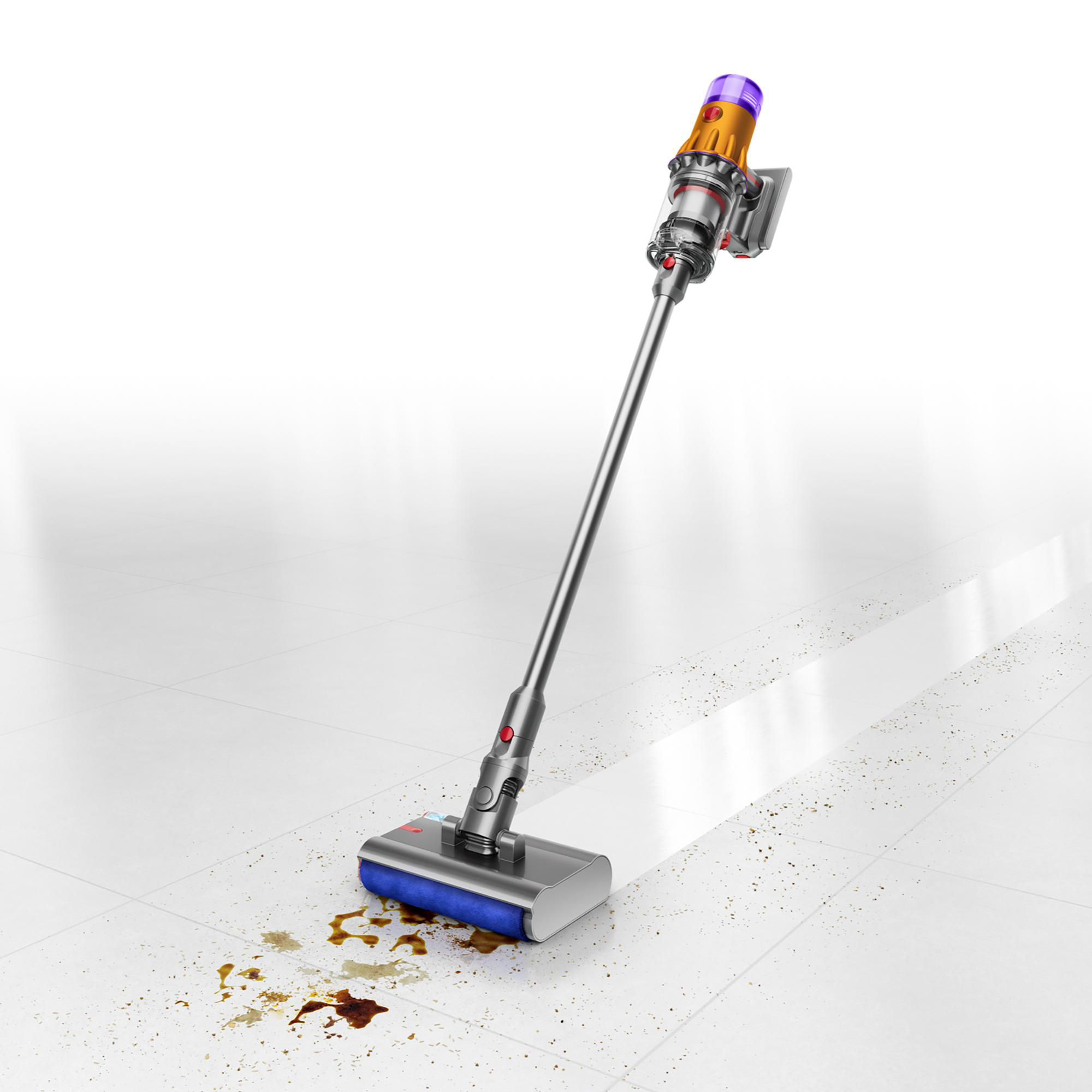 Ein Dyson-Staubsauger reinigt einen weiß gefliesten Boden mit Verschüttungen. Der Staubsauger ist orange und silber.