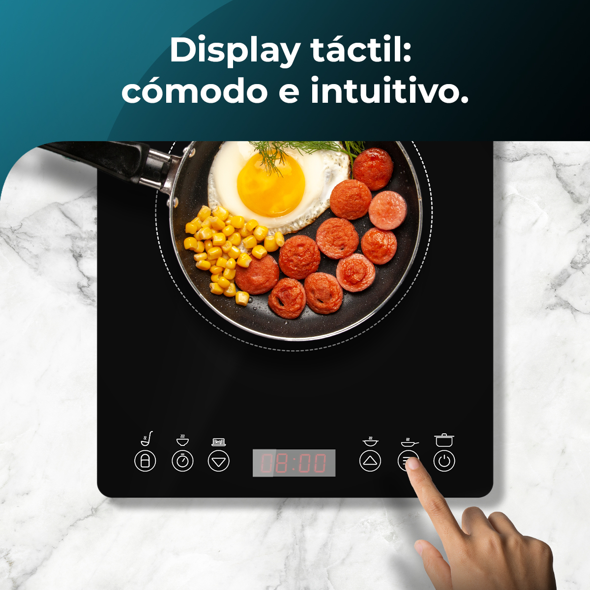 Una mano toca una estufa negra con comida en una sartén. La sartén contiene huevos, salchichas y maíz. En el fondo, una superficie de mármol.