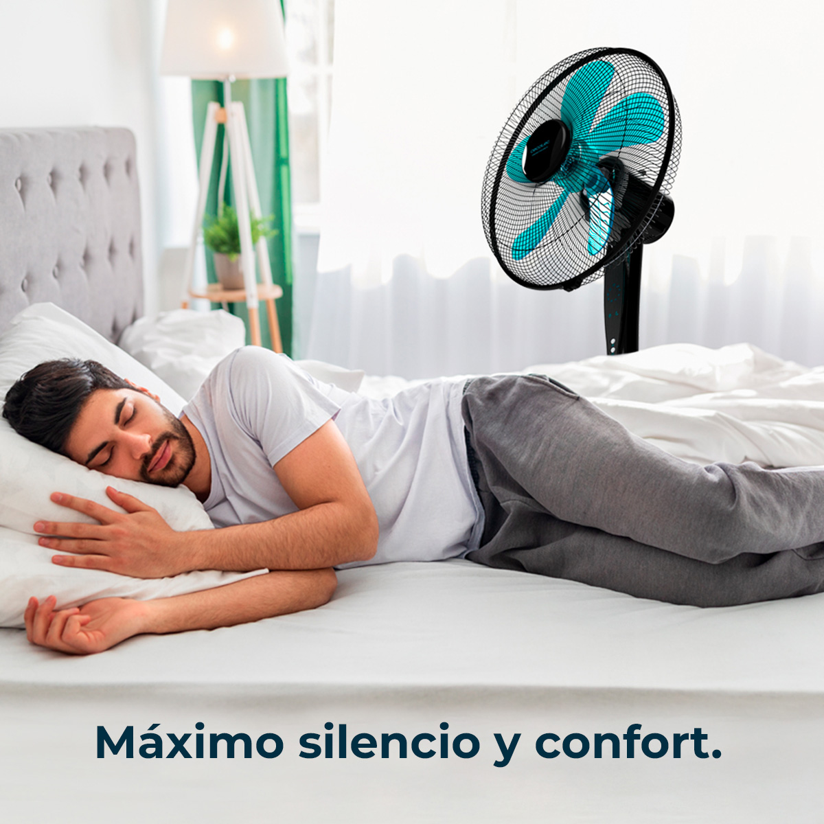 Un hombre duerme en una cama con un ventilador. El ventilador tiene aspas azules. El texto dice: Máximo silencio y confort.