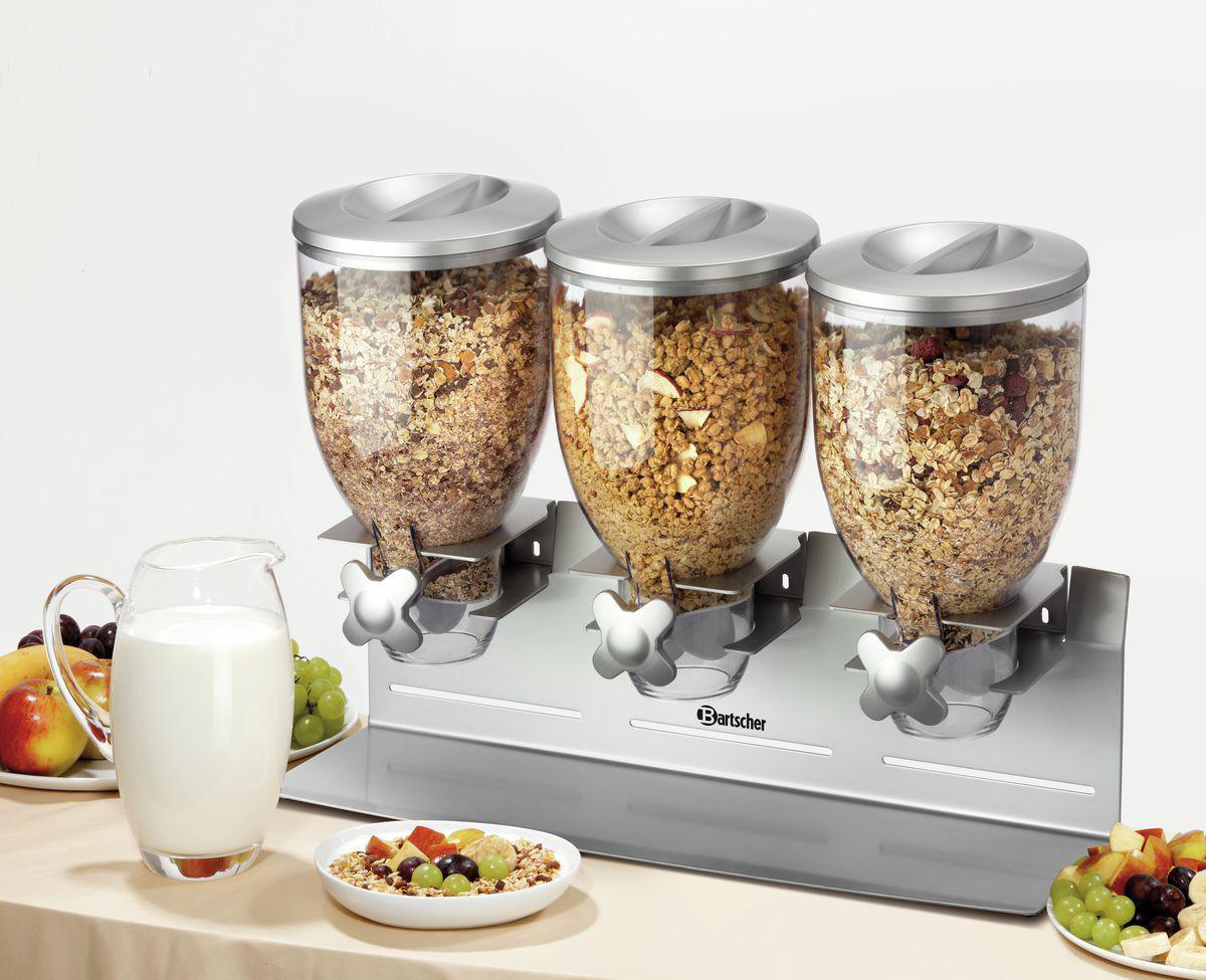 Drei Müslispender mit verschiedenen Cerealien. Milch und Früchte stehen auf dem Tisch. Eine gesunde Frühstücksumgebung.