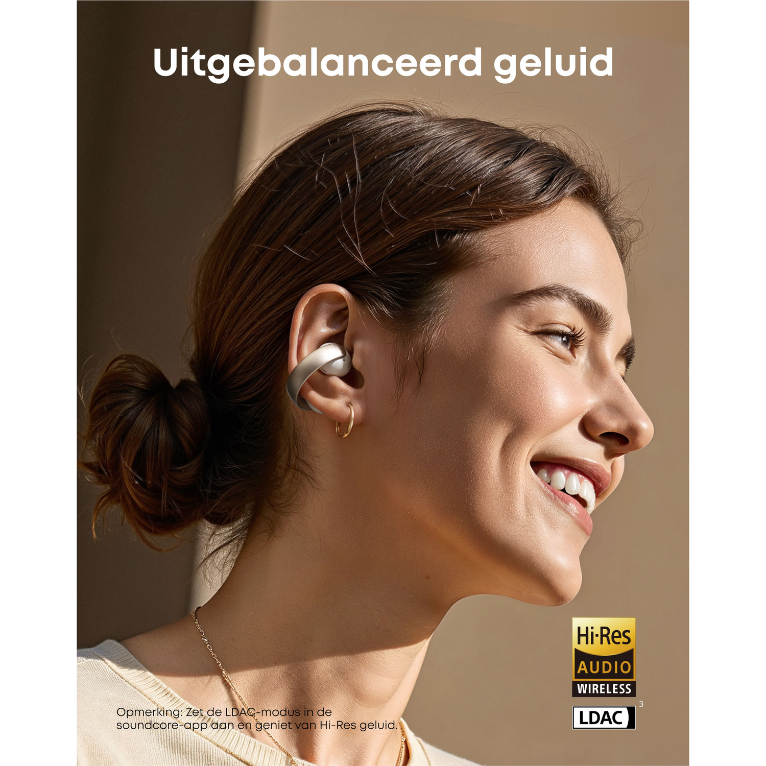 Een vrouw draagt een oortelefoon. Ze glimlacht, heeft een knot, een gouden ketting en een gouden oorbel. Tekst zegt 'Uitgebalanceerd geluid'.