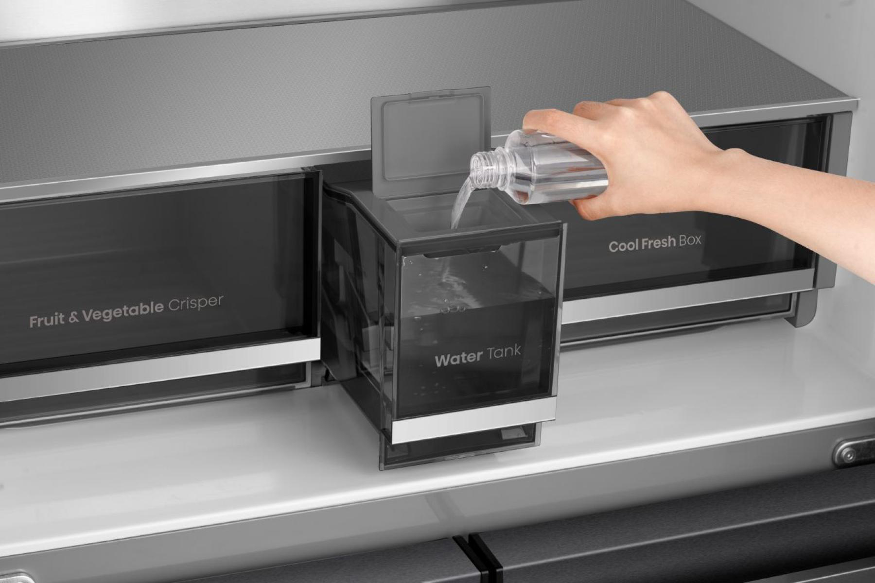 Eine Hand gießt Wasser aus einer Flasche in einen Wassertank in einem Kühlschrank. Der Tank ist mit 'Water Tank' beschriftet.