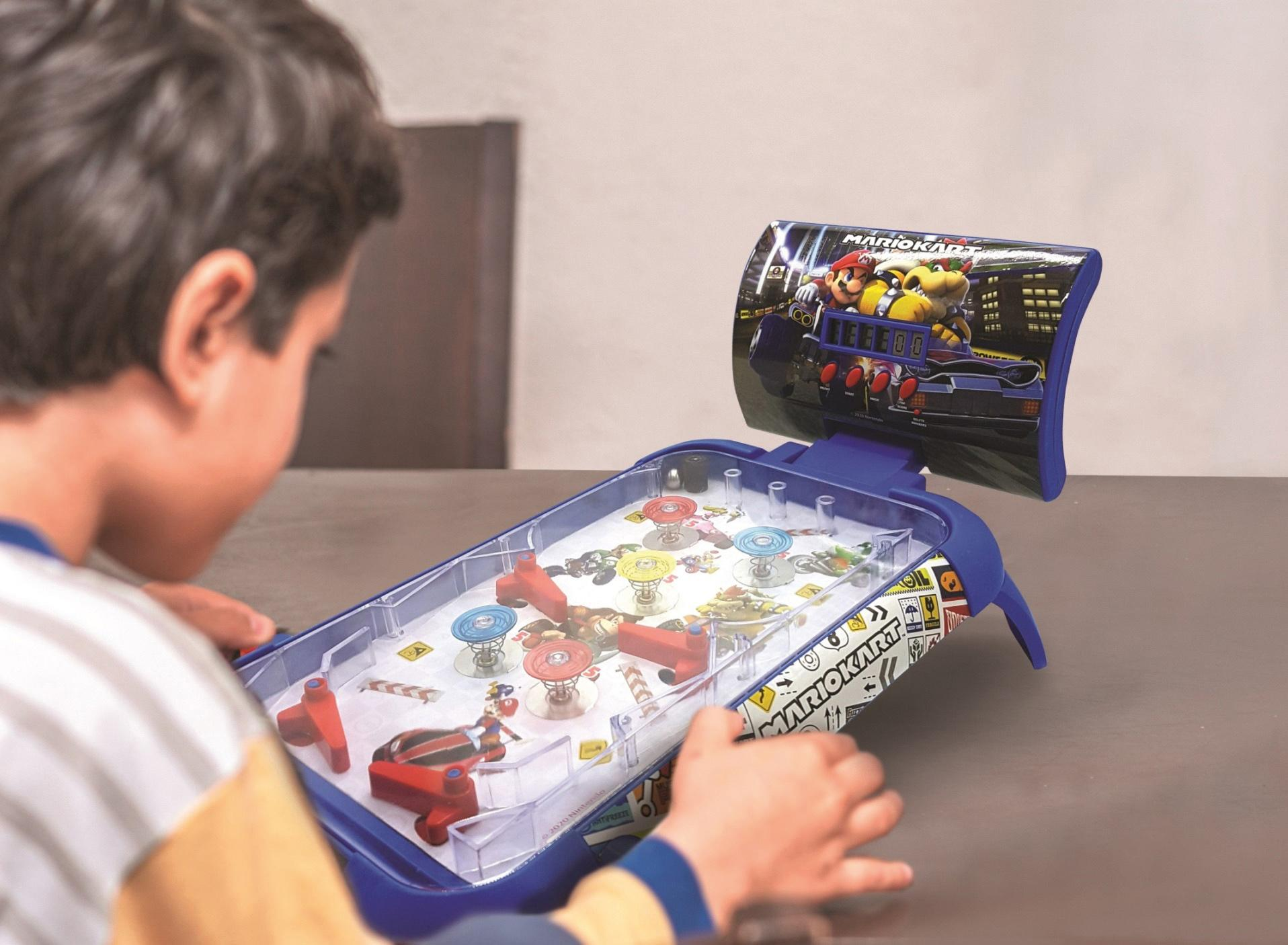 Ein Kind spielt ein Mario Kart Flipper Spiel. Das Spiel ist blau, mit Mario-Charakteren. Die Hände des Kindes sind sichtbar.