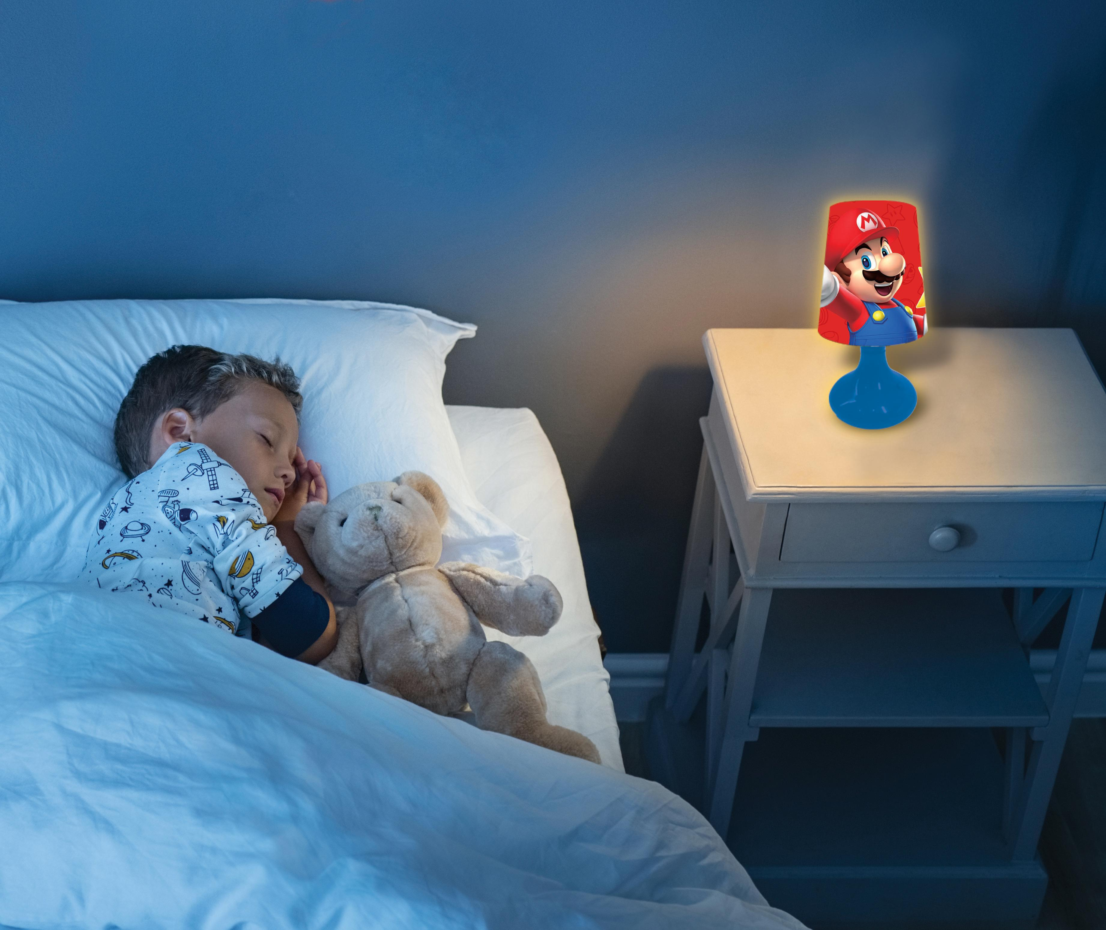 Ein Junge schläft im Bett mit einem Teddybär. Eine Mario-Lampe steht auf einem Nachttisch.