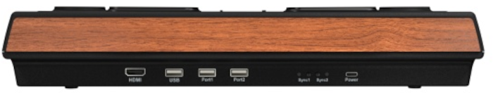 Un appareil rectangulaire avec un dessus en grain de bois et une base noire. Il comporte des ports étiquetés HDMI, USB, etc. Le bas comporte plus de ports.