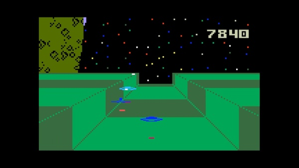 Scène de jeu vidéo rétro. Premier plan vert avec paysage pixélisé. OVNI, score 7840 et ciel étoilé.
