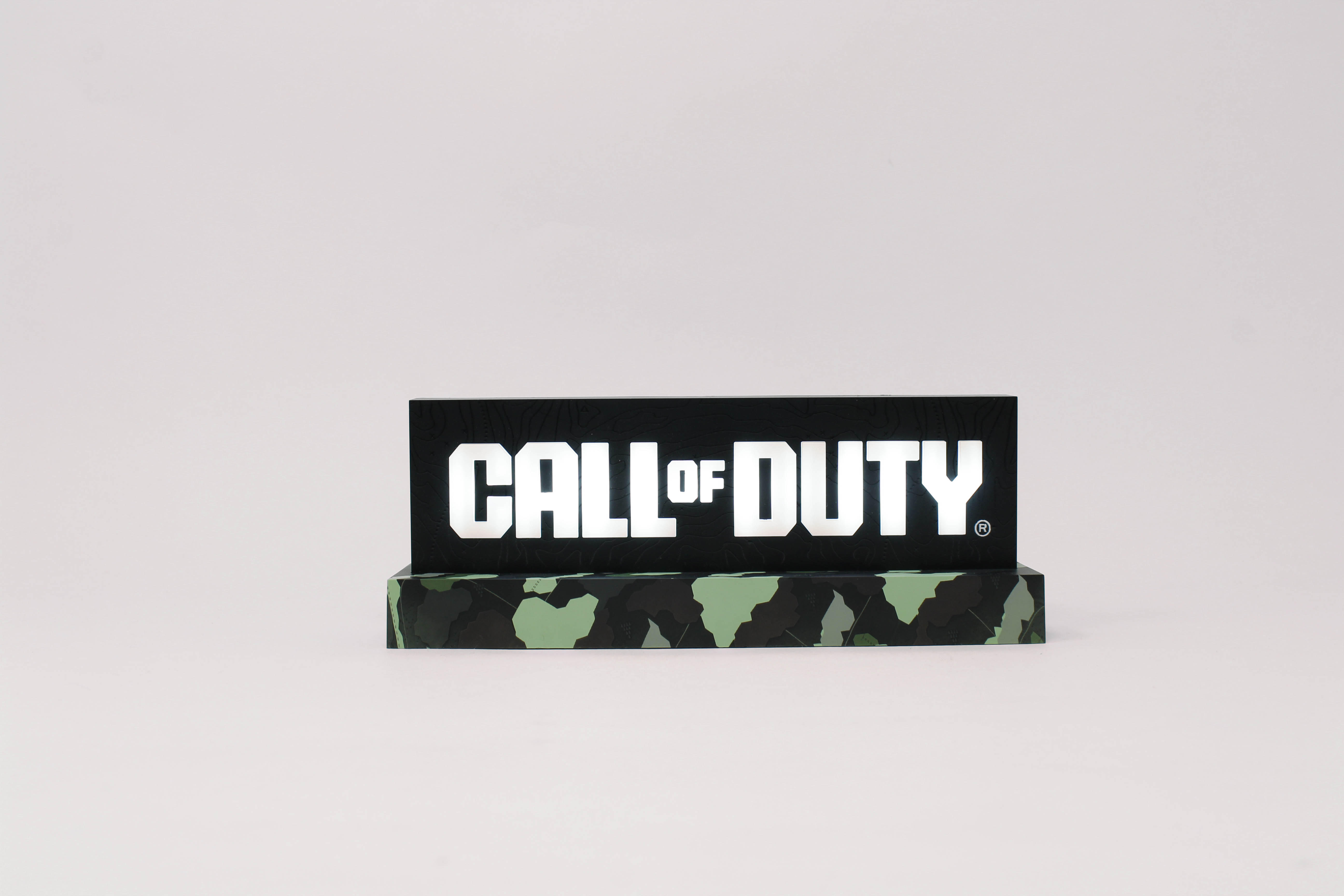 Ein 'Call of Duty'-Schild. Das Schild ist schwarz mit weißer Schrift und einem grünen Camouflage-Sockel. Weißer Hintergrund.