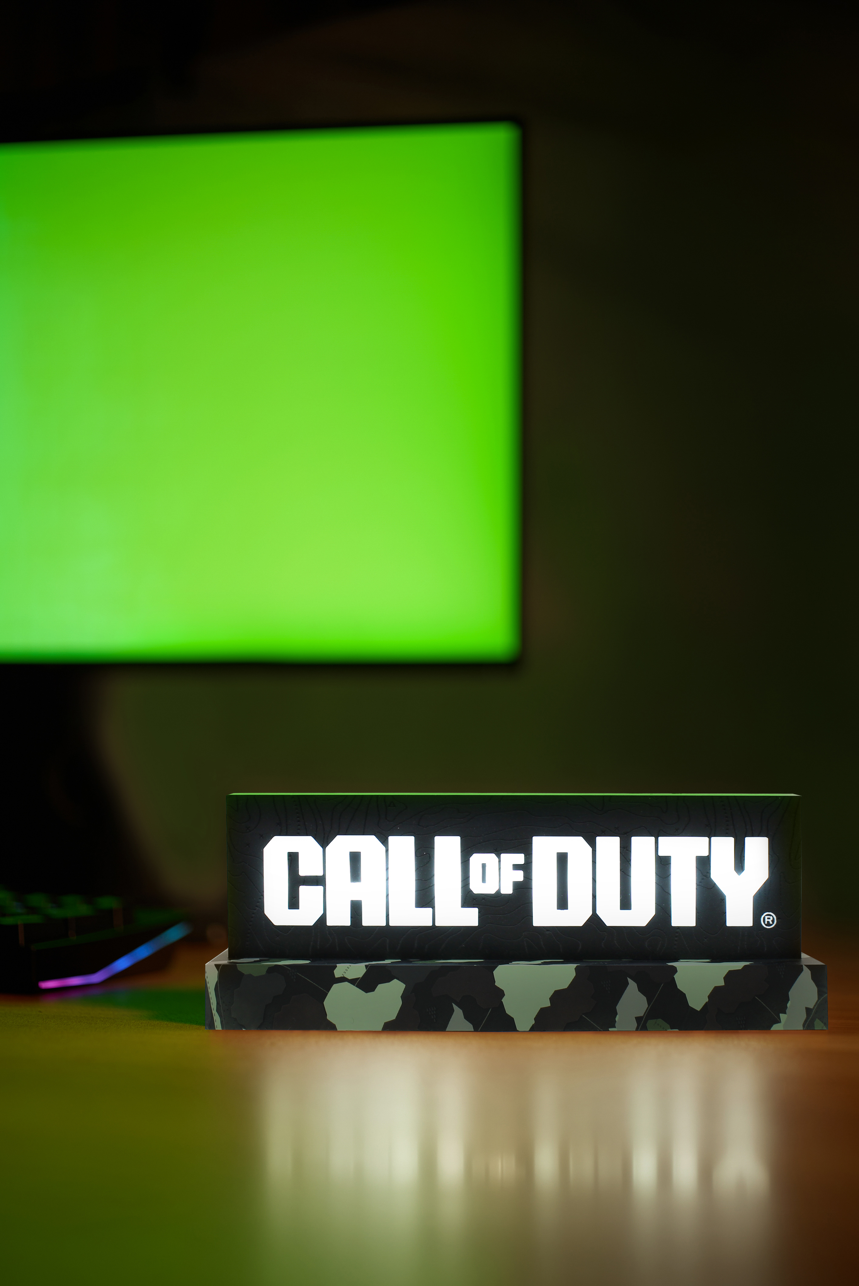 Leuchtendes Call of Duty-Schild auf einem Holzschreibtisch. Ein Greenscreen und eine Tastatur sind sichtbar.