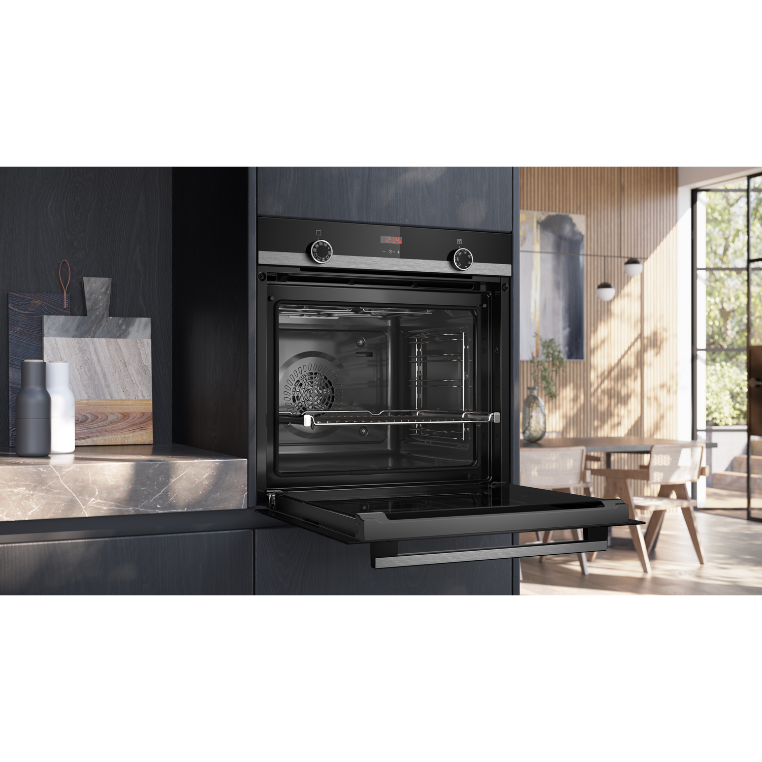 Open oven in een moderne keuken. Donkere kasten, marmeren aanrecht en uitzicht op een eethoek door een groot raam.