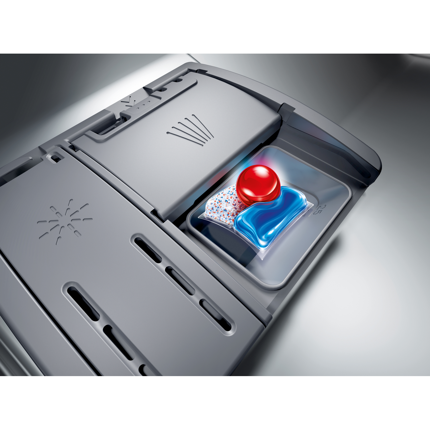 Dishwasher detergent compartment open. A red button and a blue and white detergent pod are visible in the tray. Gray machine.