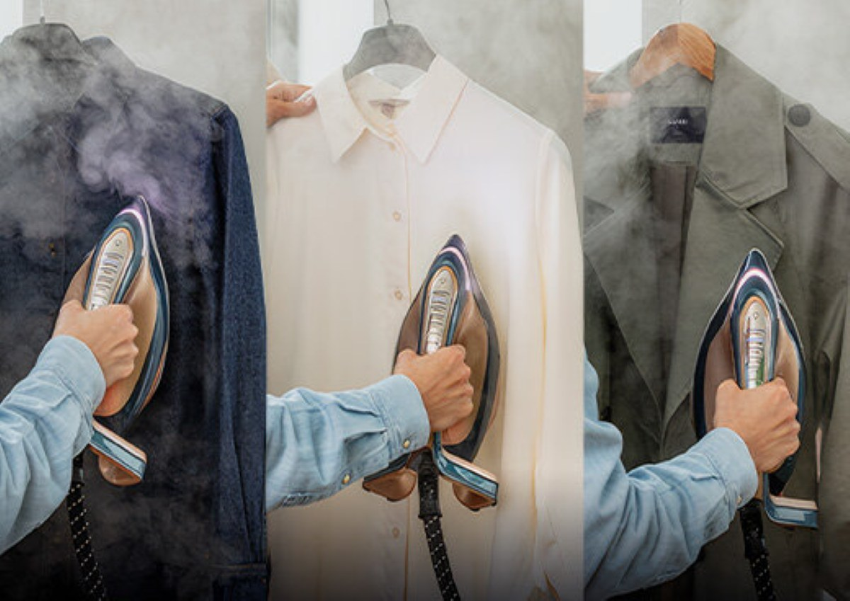 Trzy ubrania są parowane. Kurtka dżinsowa, biała koszula i zielony płaszcz. Każdy prasowany przez rękę. Para unosi się w górę.