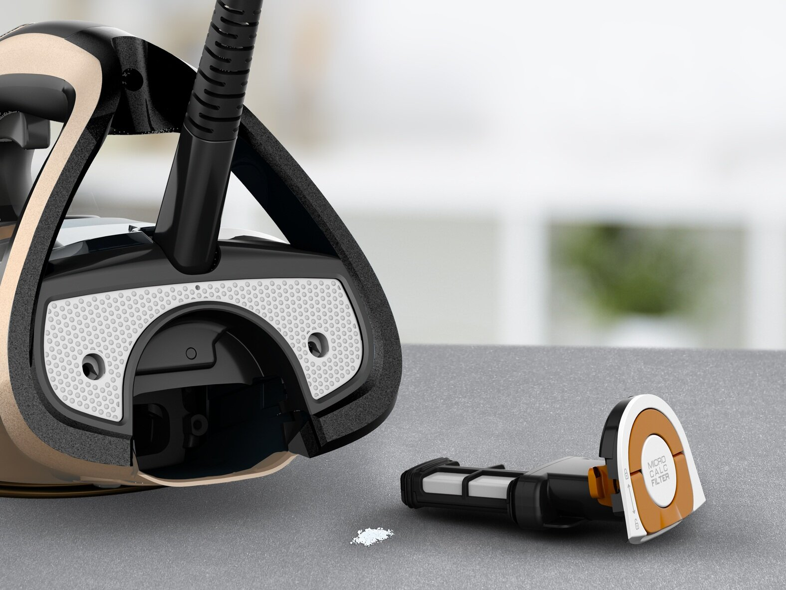 Żelazko z filtrem, zdemontowane. Czarne i złote żelazko, filtr po prawej, biały proszek z przodu. Tło: szara powierzchnia, nieostre.