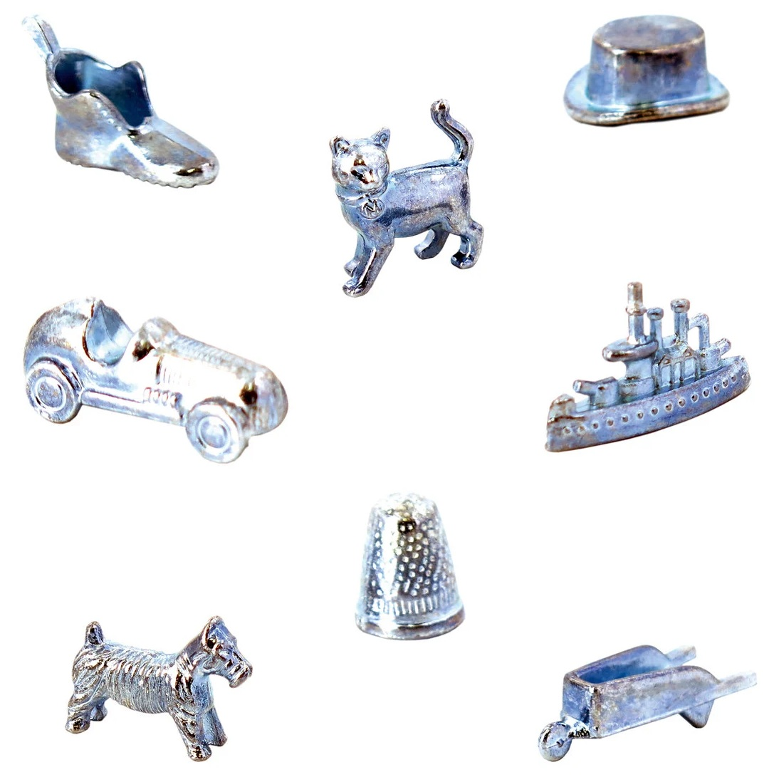 Figury z gry Monopoly: but, kot, cylinder, samochód, statek, naparstek, pies i taczka, wszystko w metalicznym srebrze.