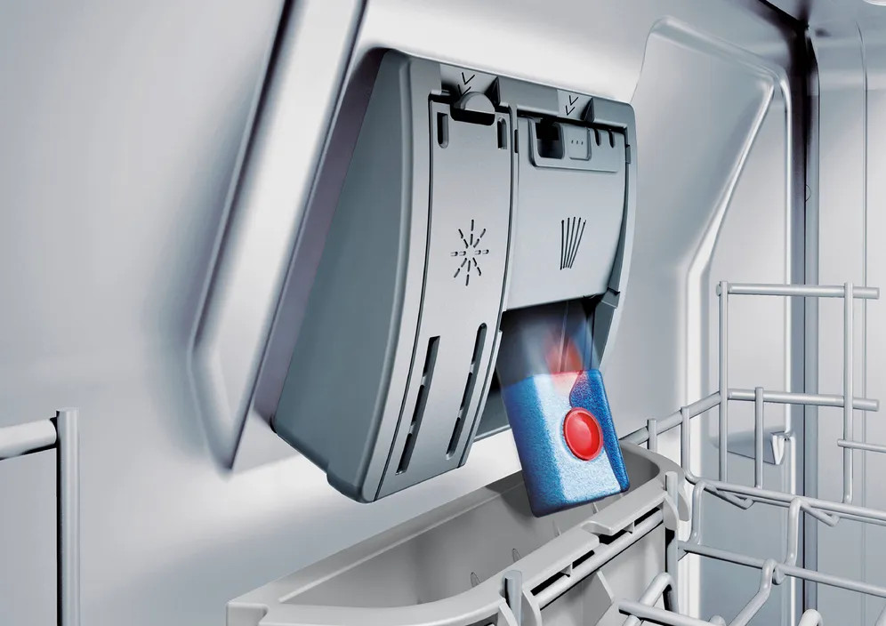 W zmywarce kapsułka z detergentem z czerwonym środkiem znajduje się w szarym dozowniku.