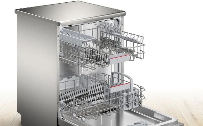 Otwarta zmywarka ze stali nierdzewnej z widocznymi półkami i koszami. Górna półka ma przybory. Dolna półka ma talerze i kosz na sztućce.