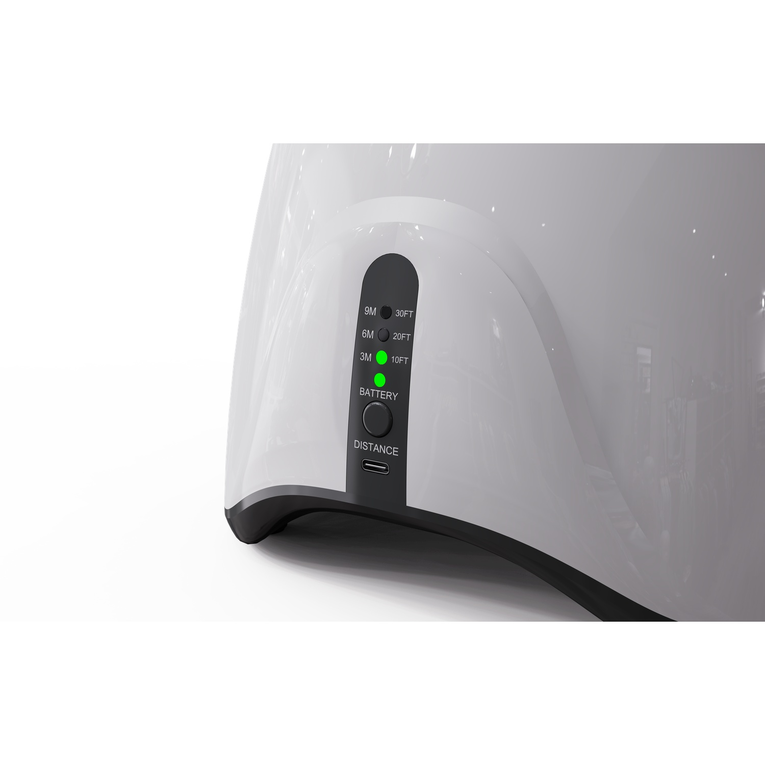 A white device with a black panel showing distance and battery status. A green light indicates operation. USB port is visible.