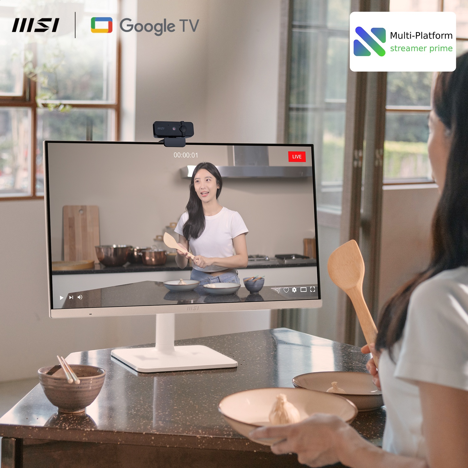 Woman cooking, watching a cooking live stream on a monitor with a webcam. There are bowls, a wooden spoon and a plate in the scene.
