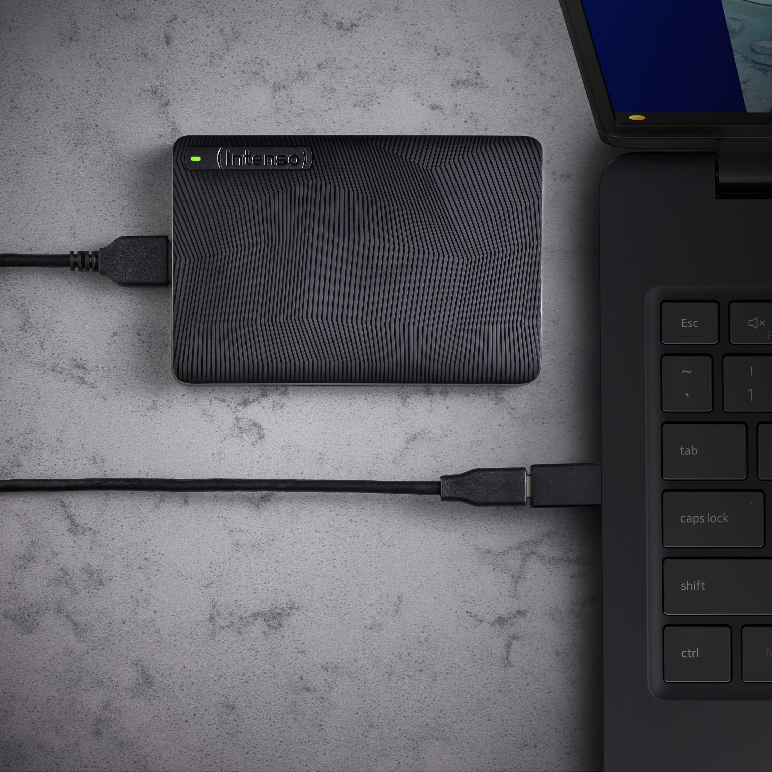 Eine schwarze externe Festplatte ist mit einem Laptop verbunden. Die Festplatte ist mit Intenso beschriftet.