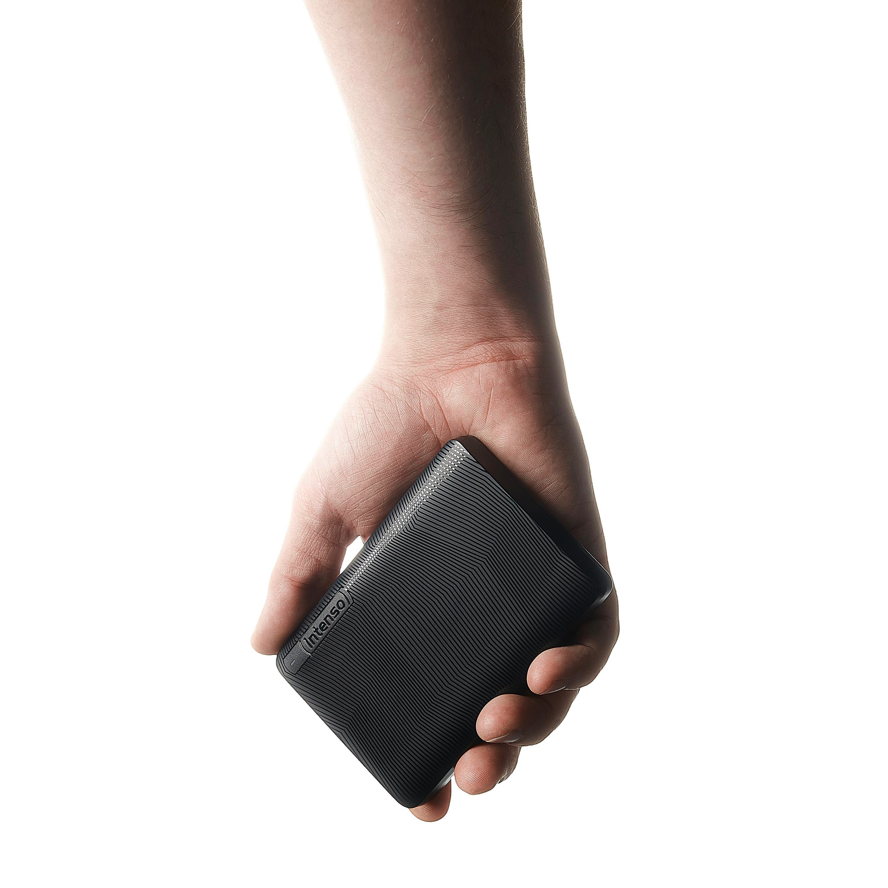 Eine Hand hält eine schwarze externe Festplatte mit dem sichtbaren Markennamen 'Intenso'. Der Hintergrund ist weiß.