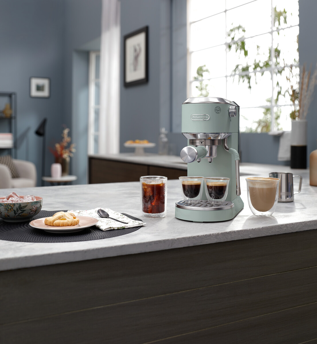 Egy eszpresszógép két csésze eszpresszóval, egy pohár jegeskávéval és egy latte-val a pulton.