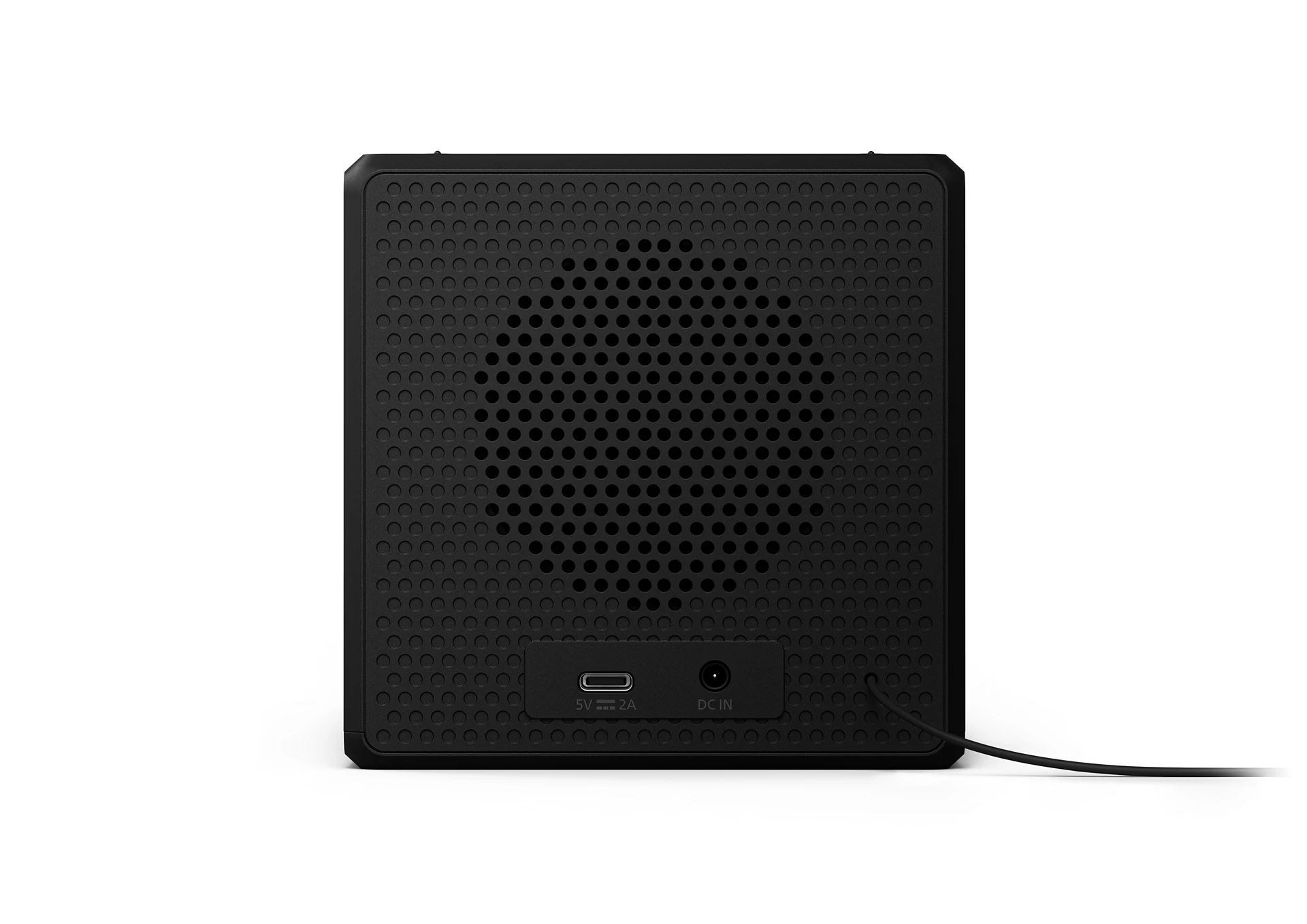 Altavoz negro con frontal perforado. Tiene puerto USB, puerto DC IN y cable de alimentación. El altavoz está sobre un fondo blanco.