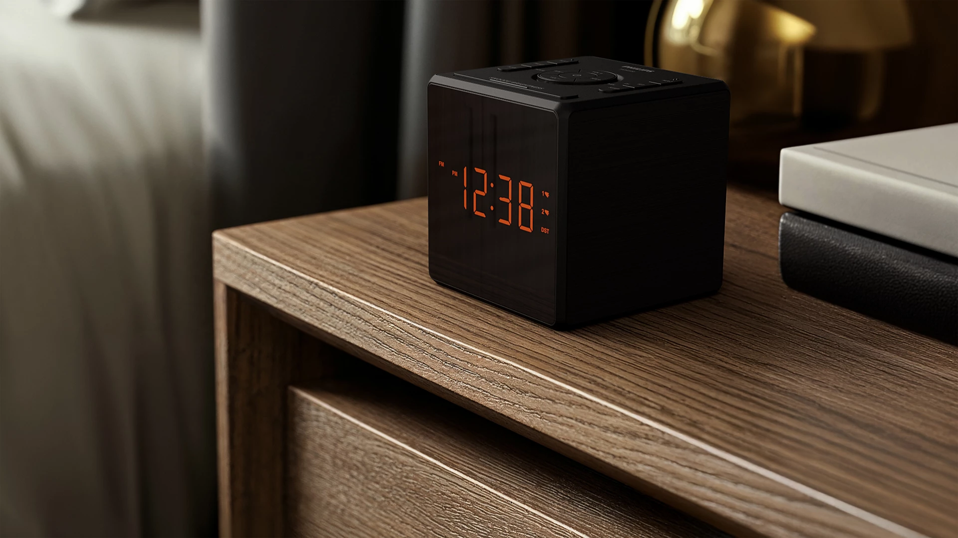 Un reloj digital negro que muestra 12:38, sobre una mesita de noche de madera con libros. El fondo está borroso.